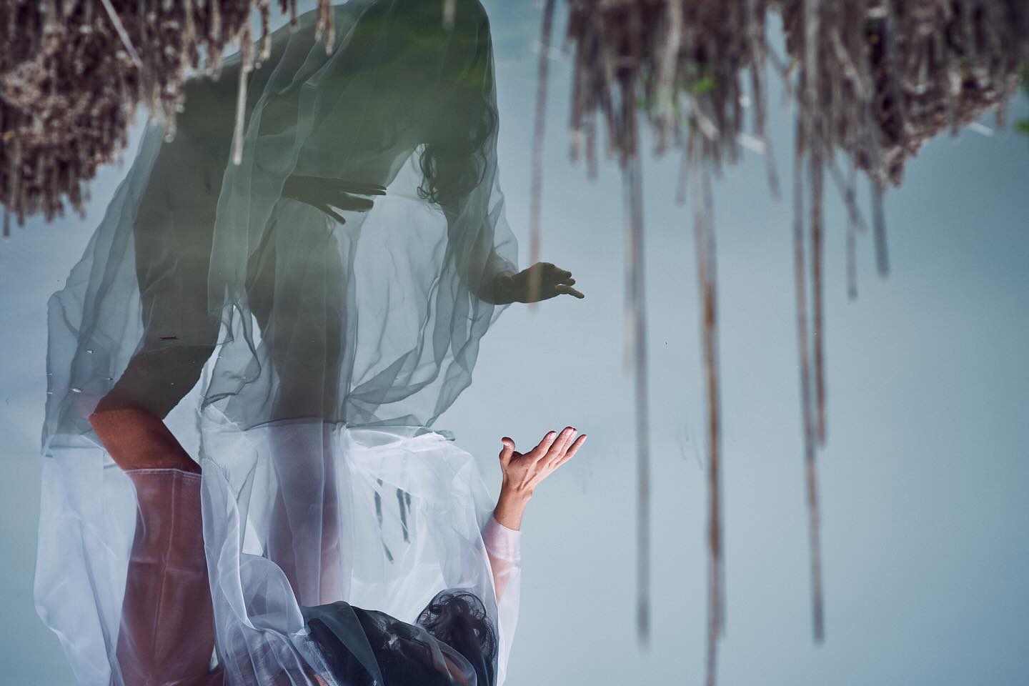 A woman in white beneath hanging dried flowers, during the Art of Ritual residency