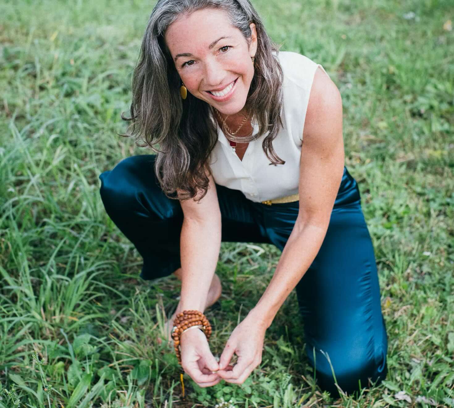 Schuyler Brown kneeling in long grass, smiling