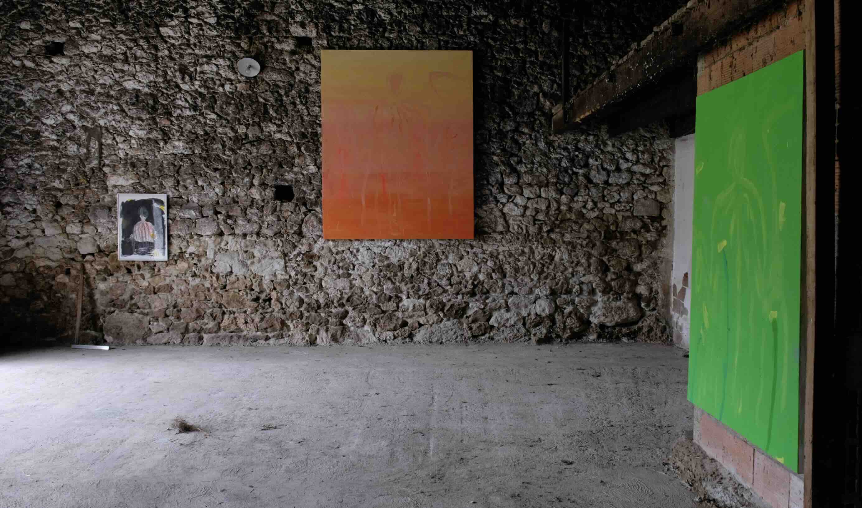 Paintings hung on the stone walls of a barn at the Impermanence exhibition
