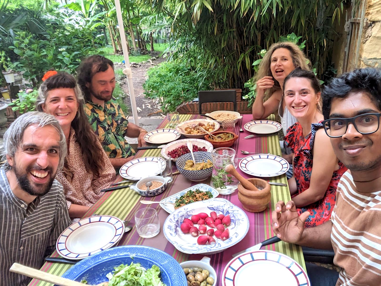 Friends laughing around a long table in a garden